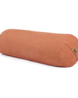 A pink or orange cylindrical bolster pillow with a small cork brand tag, shown on a clean white background