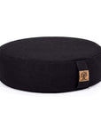 A round black fabric meditation cushion with a small cork patch on the side, photographed on a clean white background