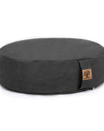 A dark charcoal gray round meditation cushion with a small cork brand tag on the side, photographed on a clean white background