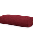 A deep burgundy red rectangular bolster pillow with a textured fabric cover, shown on a clean white background
