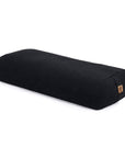A black rectangular bolster pillow with a small cork tag, shown on a clean white background