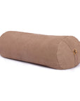 A cylindrical bolster pillow in a warm beige / brown colour, made of textured fabric, shown on a clean white background with a small cork tag on one end