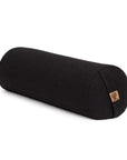 A black cylindrical yoga bolster pillow with a small cork patch on the end, shown on a clean white background