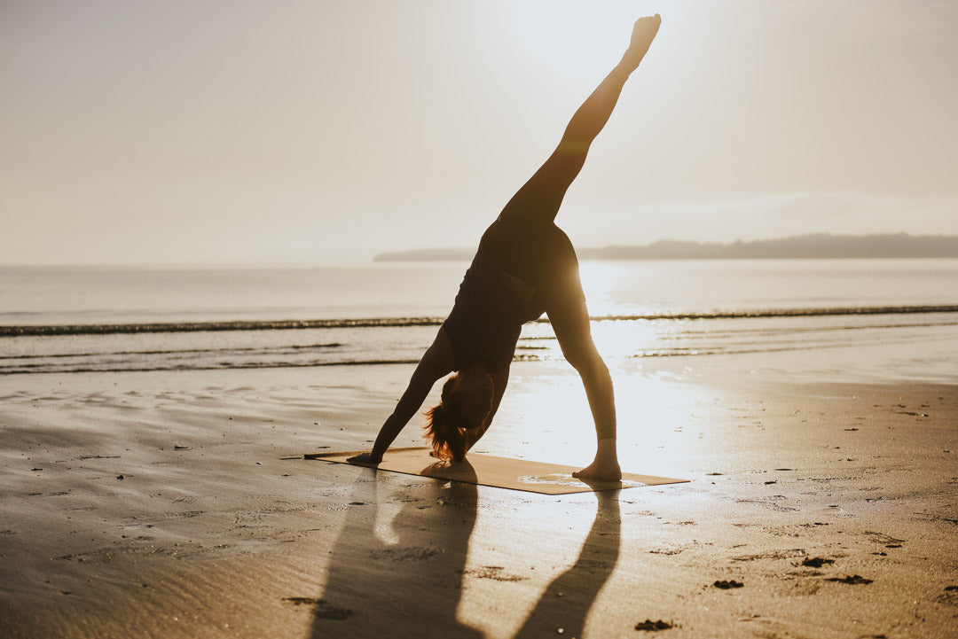 Woman practising on yoga mat on NZ beach